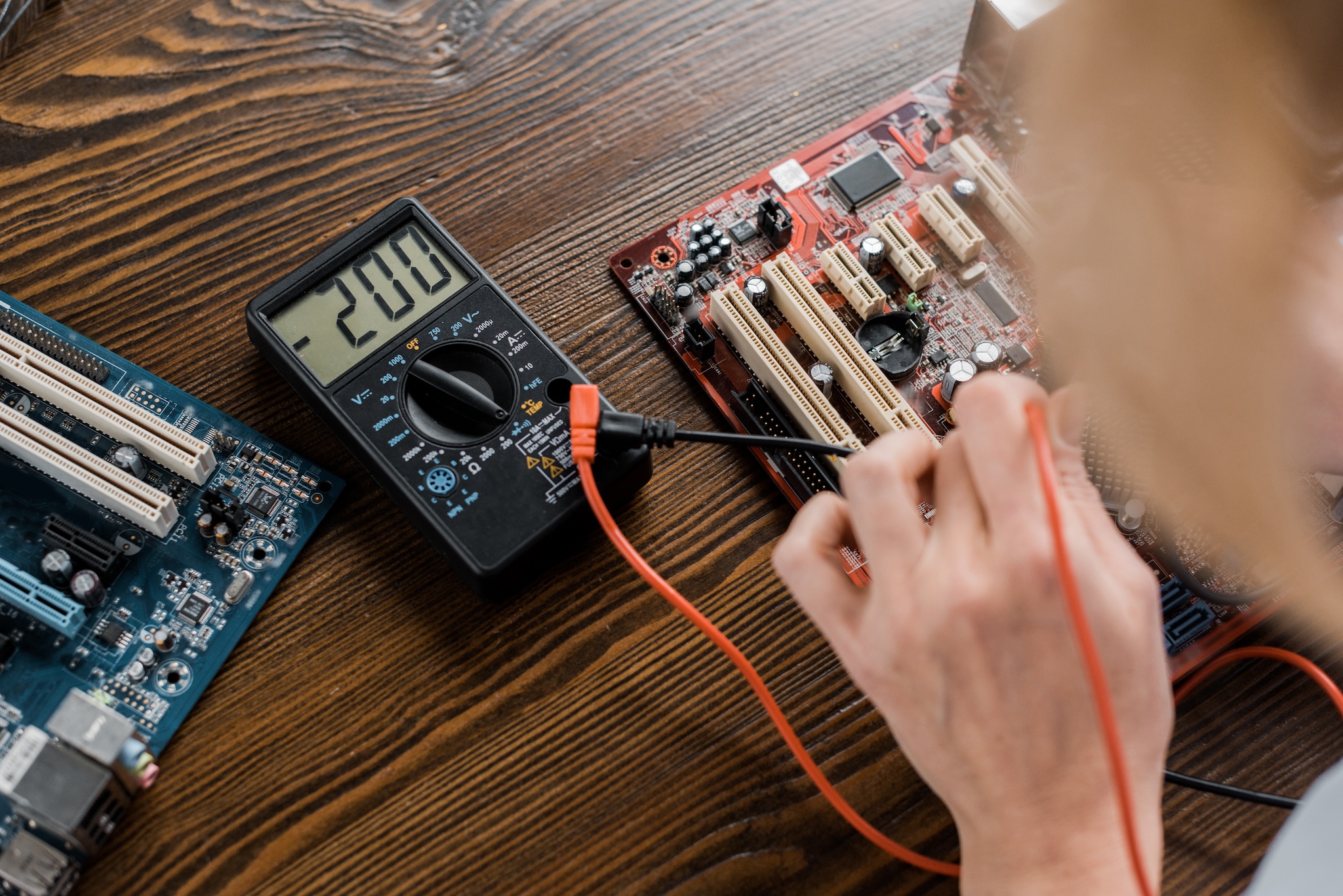 cropped shot of electric engineer with tester examining motherboard